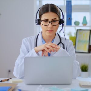 A woman in white lab coat using laptop computer.