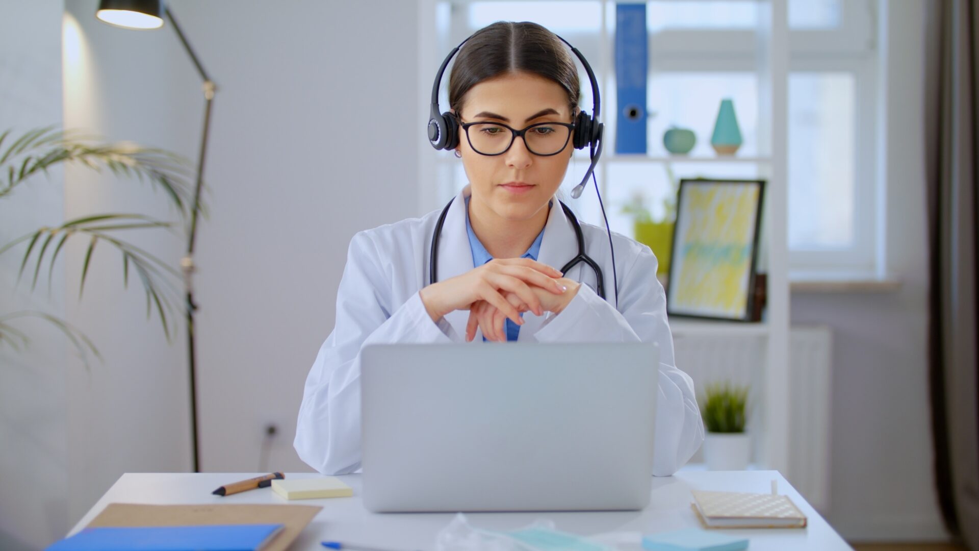 A woman in white lab coat using laptop computer.